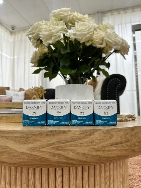 Daxxify cartons displayed on a wooden table beside white roses at the practice.