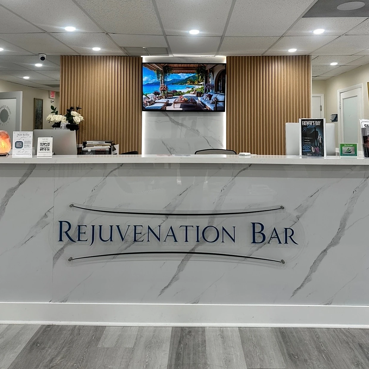 The Rejuvenation Bar Miami reception desk with the branded sign and wood slat wall.